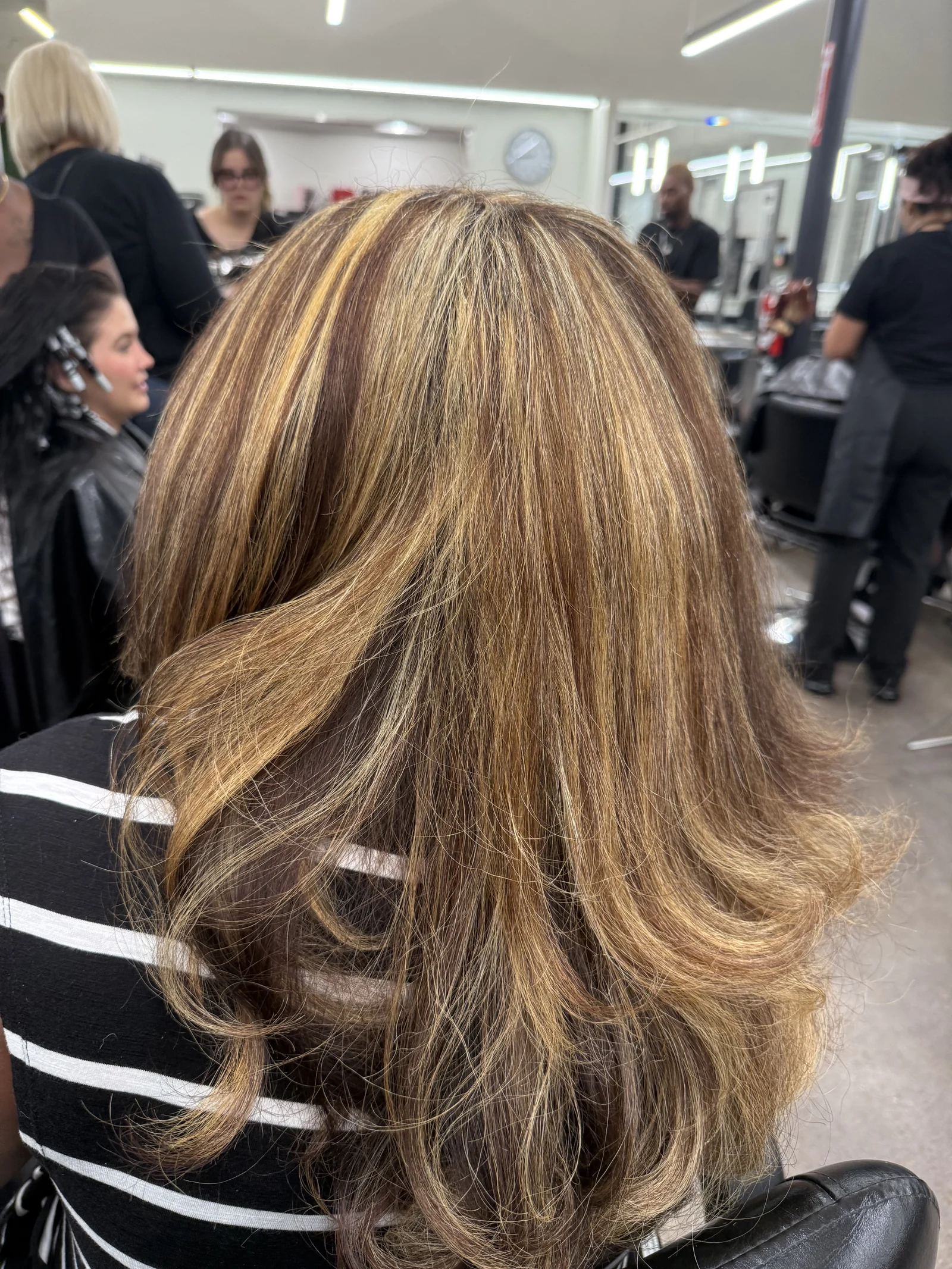 Warm blonde highlights through layered, shoulder-length hair, viewed from behind.